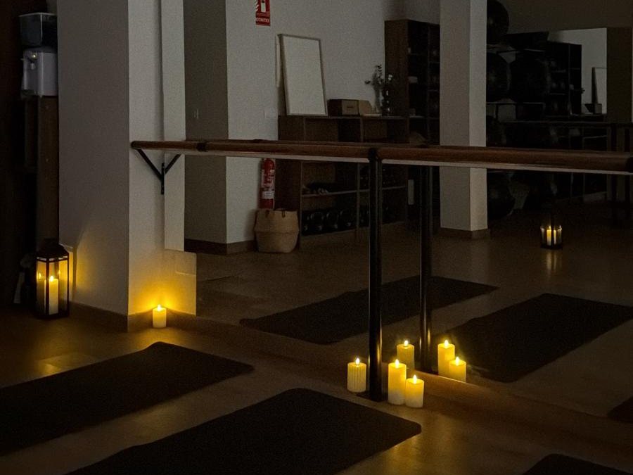 La sala a oscuras, con esterillas en el suelo y velas encendidas junto a la barra